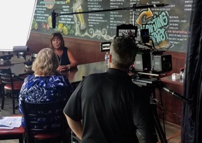 Cathy Dipierro interviews Sher Grogg, a home fire sprinkler advocate, on camera in a restaurant