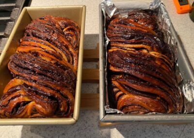 Two loaves of swirled chocolate babka in loaf pans