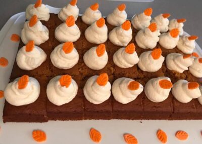 13x9 pumpkin cake cut into individual squares each topped with a dollop of frosting and a small orange fondant leaf