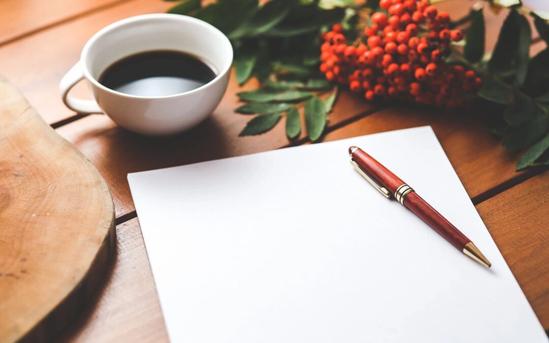 A blank page symbolizing writer's block on a desk with a pen and a cup of coffee